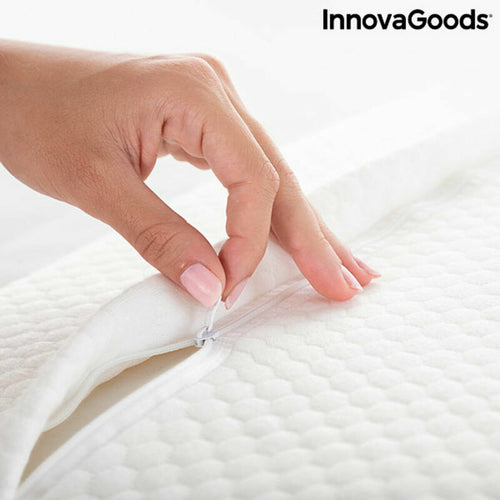 A hand unzipping the white fabric cover of a textured InnovaGoods pillow.