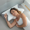 Woman sleeping on a white and grey contoured foam pillow with a textured fabric cover on a bed.